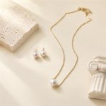 Single-pearl pendant necklace with matching pearl stud earrings laid flat