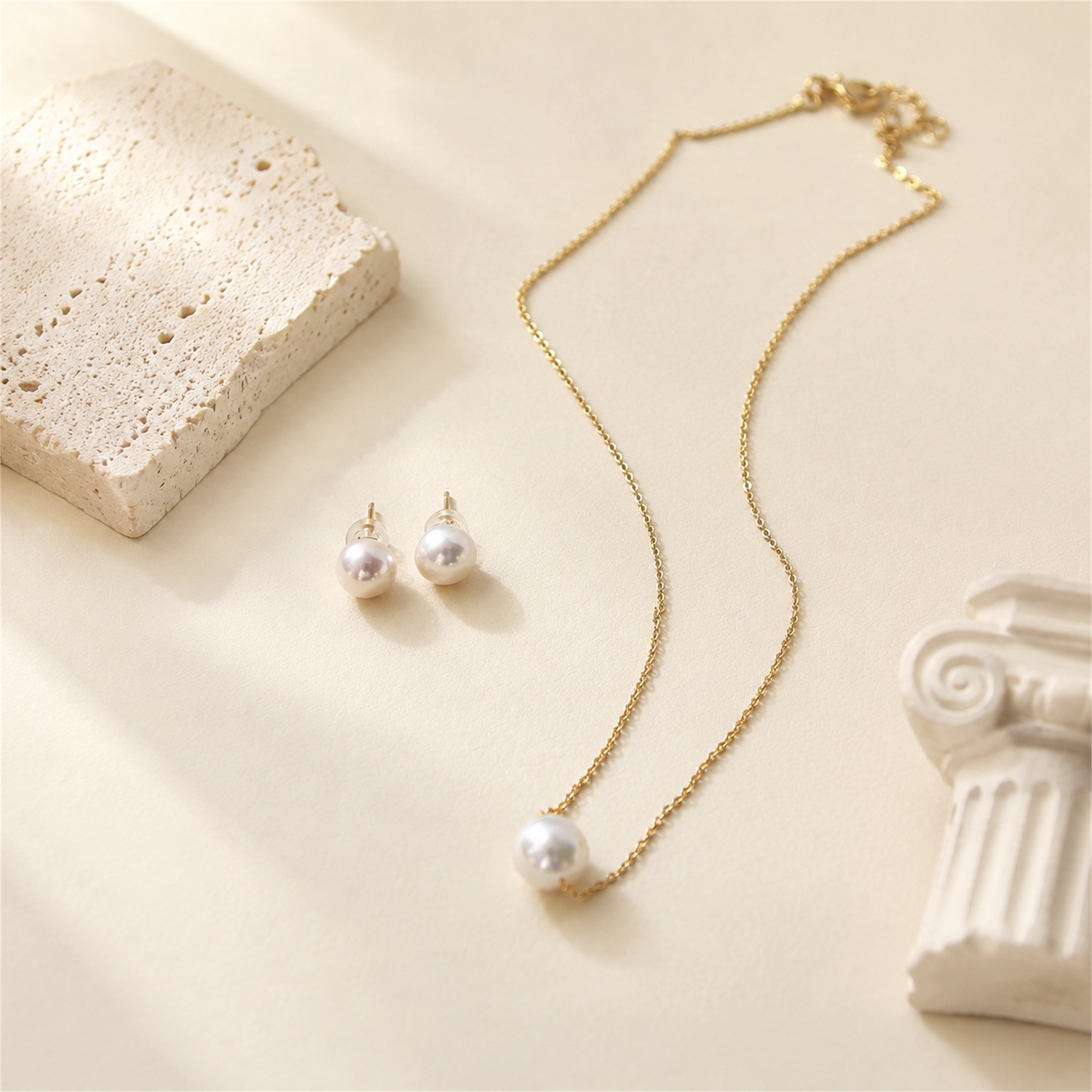 Single-pearl pendant necklace with matching pearl stud earrings laid flat