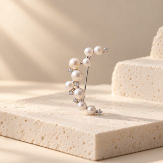 Silver-toned crescent moon brooch with graduated pearl details and small sparkling accents