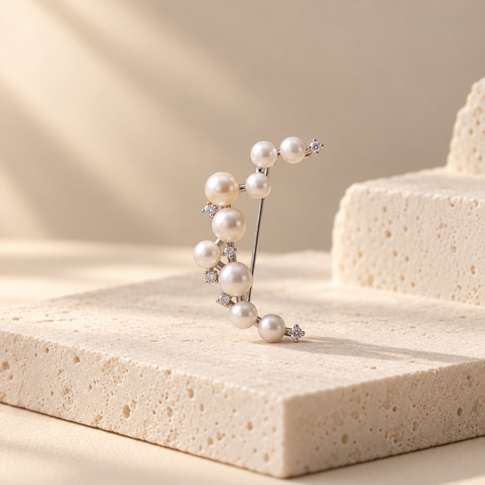 Silver-toned crescent moon brooch with graduated pearl details and small sparkling accents