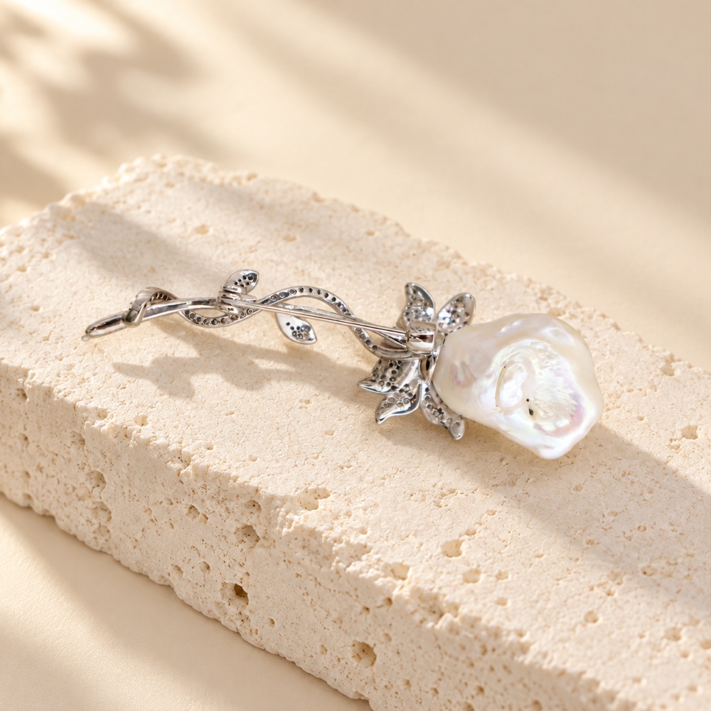 Back of baroque pearl floral brooch showing its pin fastening and curved silver-toned stem