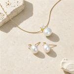 Gold-toned freshwater pearl pendant necklace and matching pearl studs laid flat