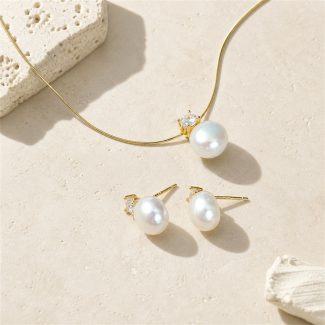 Gold-toned freshwater pearl pendant necklace and matching pearl studs laid flat