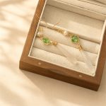 Green clover and white jade drop earrings resting in a display box