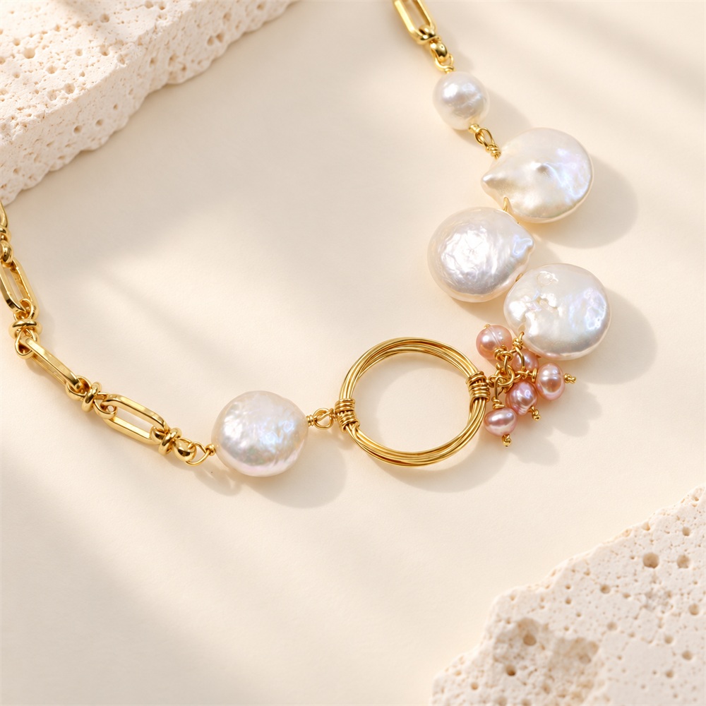 Close view of coin pearls, pink rice pearls and circular ring on an oval-link necklace