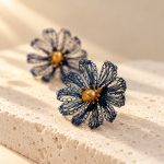 Close view of navy blue crocheted daisy earrings with golden-toned pearl centers
