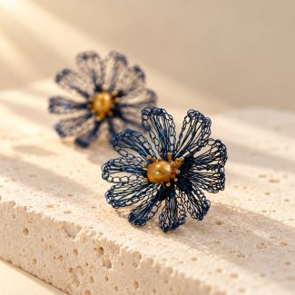 Close view of navy blue crocheted daisy earrings with golden-toned pearl centers