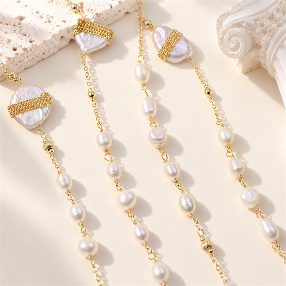 Close view of a long freshwater pearl necklace with linked pearls and gold-tone bands across large baroque pearls