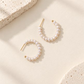 Freshwater pearl open hoop earrings laid flat, showing golden posts and curved pearl rows