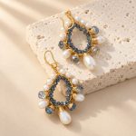 Angled view of blue crystal and pearl teardrop earrings with wire-wrapped borders and hooks