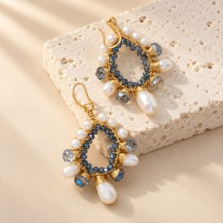 Angled view of blue crystal and pearl teardrop earrings with wire-wrapped borders and hooks