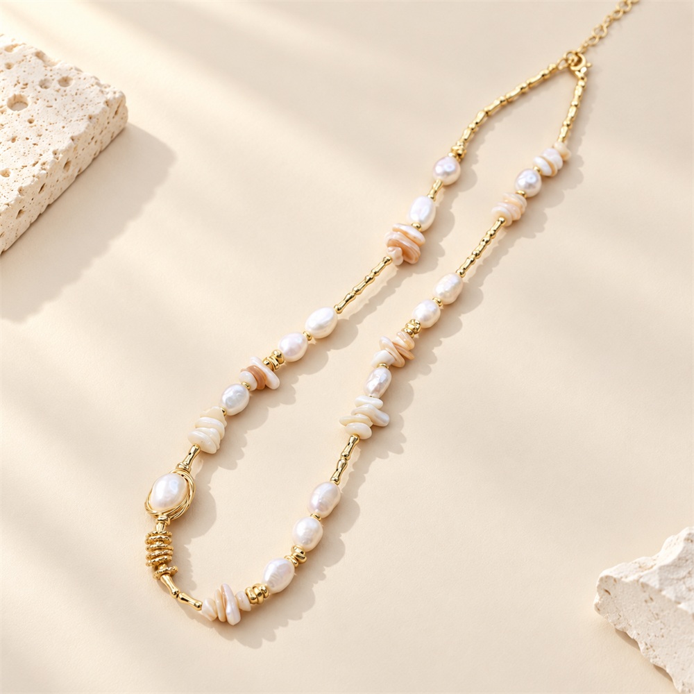 Shell fragment and freshwater pearl necklace arranged flat to show its irregular linked design