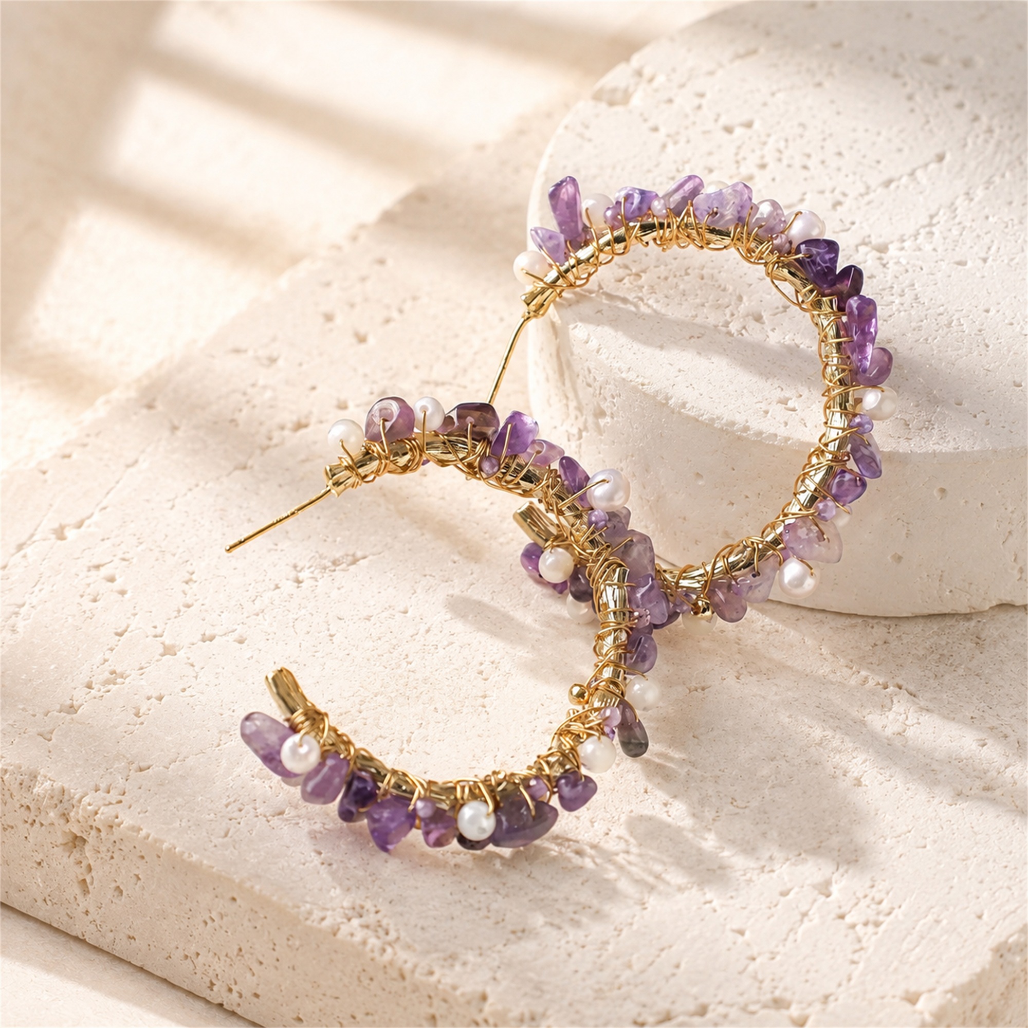 Angled view of open hoops wrapped with purple amethyst chips and small freshwater pearls