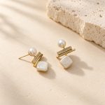 Angled view of pearl drop earrings with round tops, sparkling bars and square pearl drops