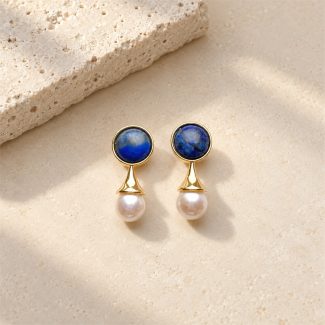 Lapis lazuli pearl drop earrings laid flat, with blue round studs above white pearls