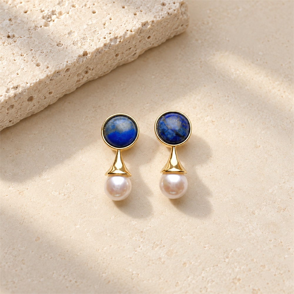 Lapis lazuli pearl drop earrings laid flat, with blue round studs above white pearls