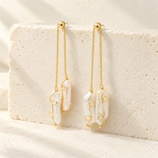 Baroque pearl drop earrings hanging from gold-toned chains, with curled wire details and staggered pearl lengths