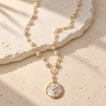Coin pearl pendant necklace with spiral gold-tone wire and linked freshwater pearls laid flat