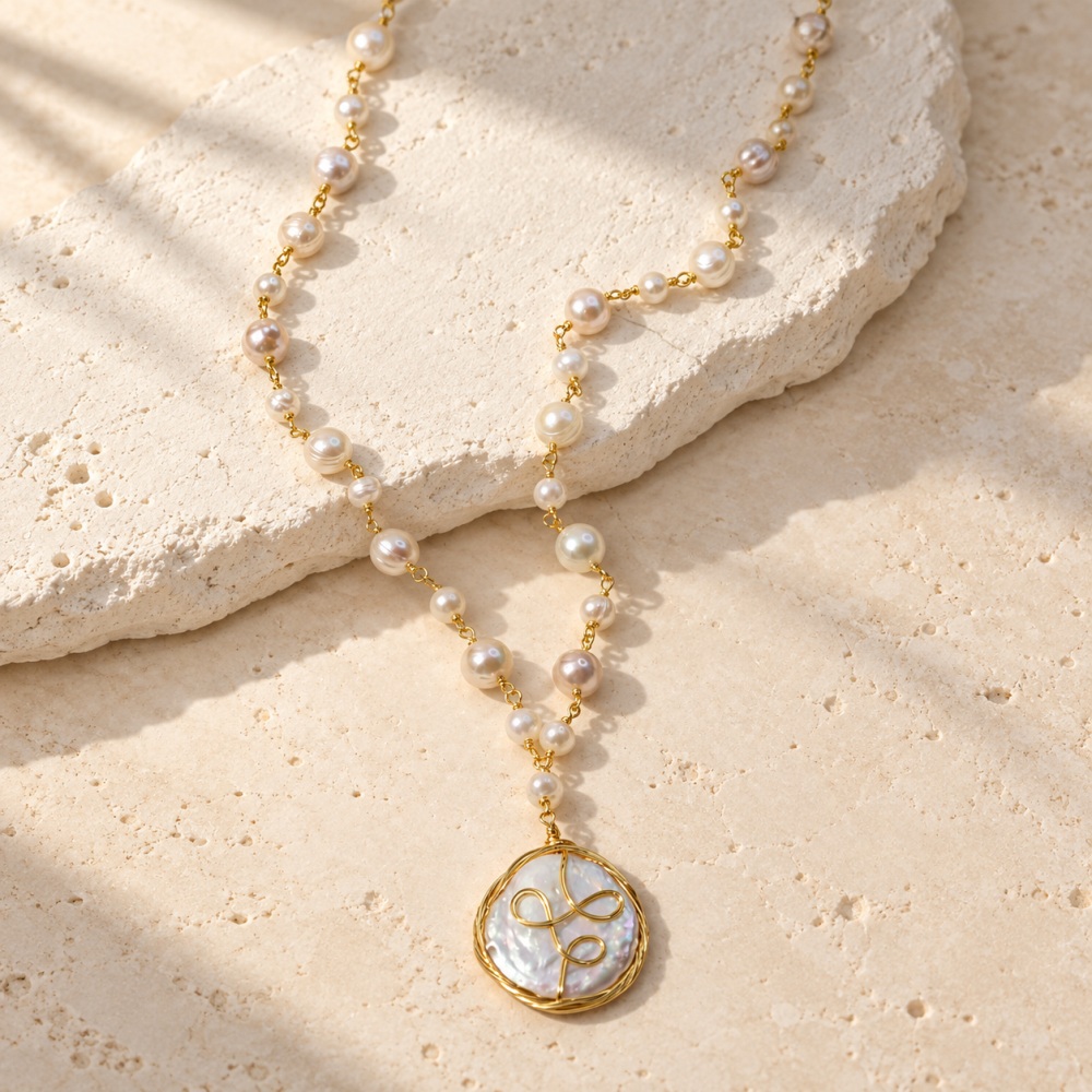 Coin pearl pendant necklace with spiral gold-tone wire and linked freshwater pearls laid flat