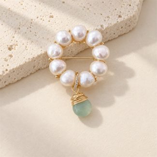Front view of freshwater pearl wreath brooch with a green jade drop and wrapped gold-tone cap