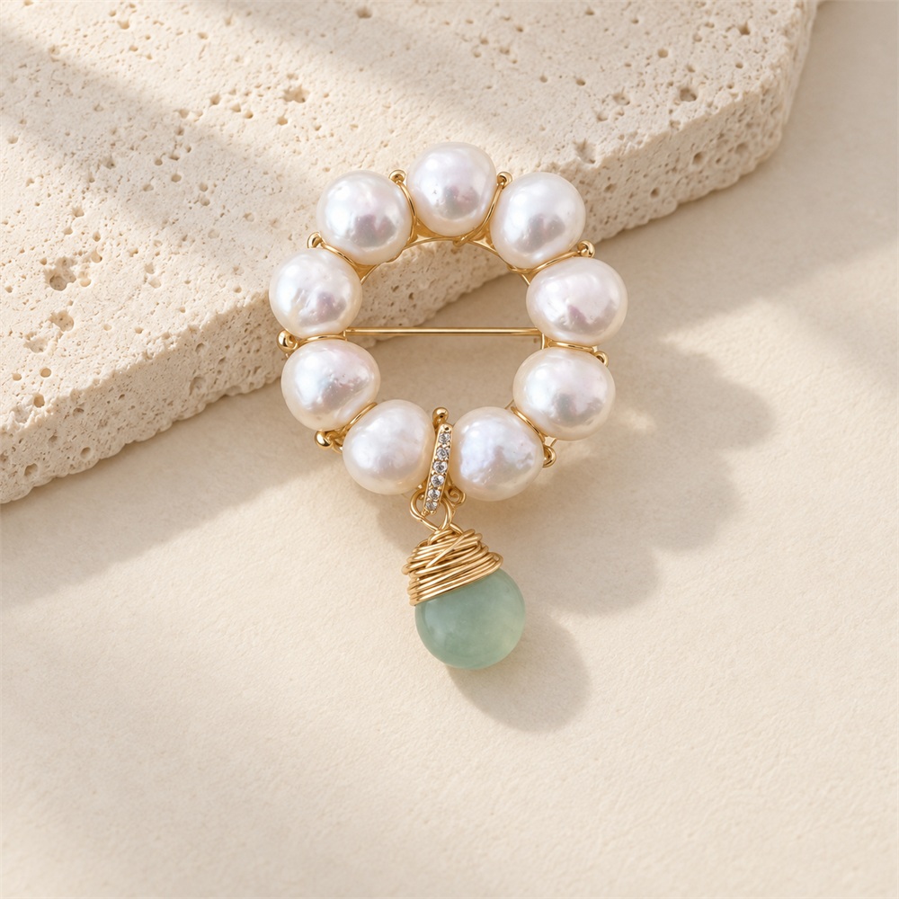 Front view of freshwater pearl wreath brooch with a green jade drop and wrapped gold-tone cap