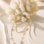 Close view of a gold-tone long necklace with irregular pearls and small clear dangling charms