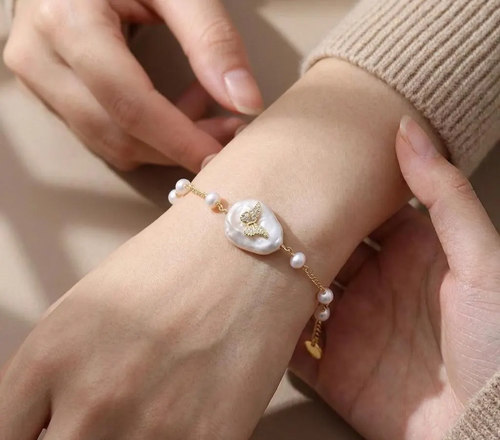 Butterfly baroque pearl station bracelet worn on a wrist