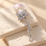 Close-up of baroque pearl brooch with sparkling flower petals and slender leaf stem