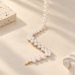 Close-up of white rice pearls and gold-toned clasp on a pearl necklace