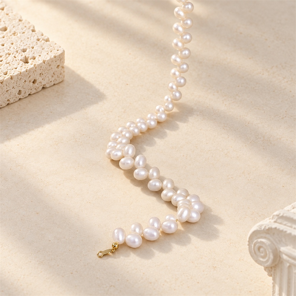 Close-up of white rice pearls and gold-toned clasp on a pearl necklace