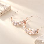 Pair of open hoop earrings with petal-shaped pearls and gold-tone details laid flat