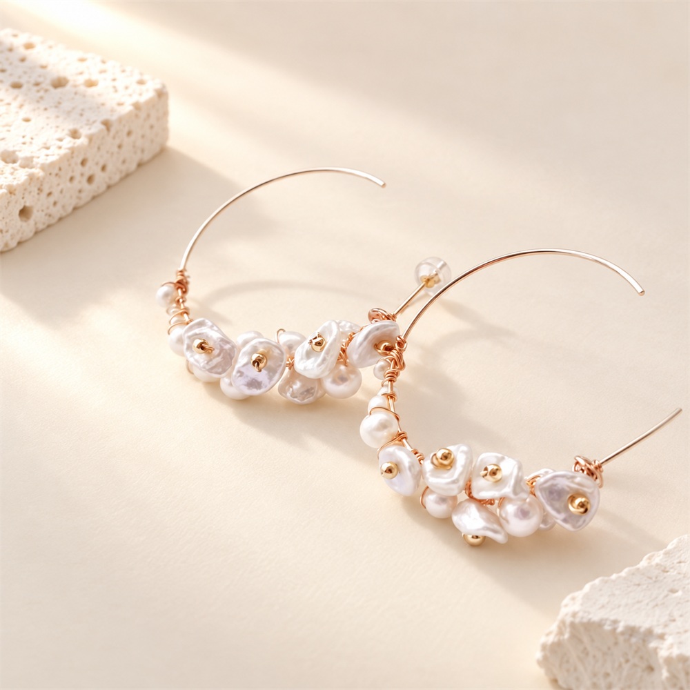Pair of open hoop earrings with petal-shaped pearls and gold-tone details laid flat