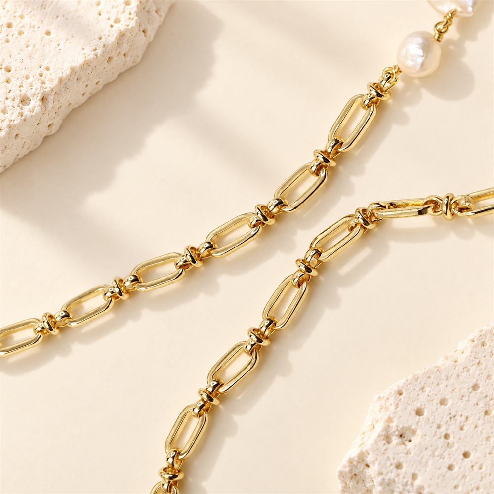 Gold-tone oval-link chain detail of a baroque pearl necklace