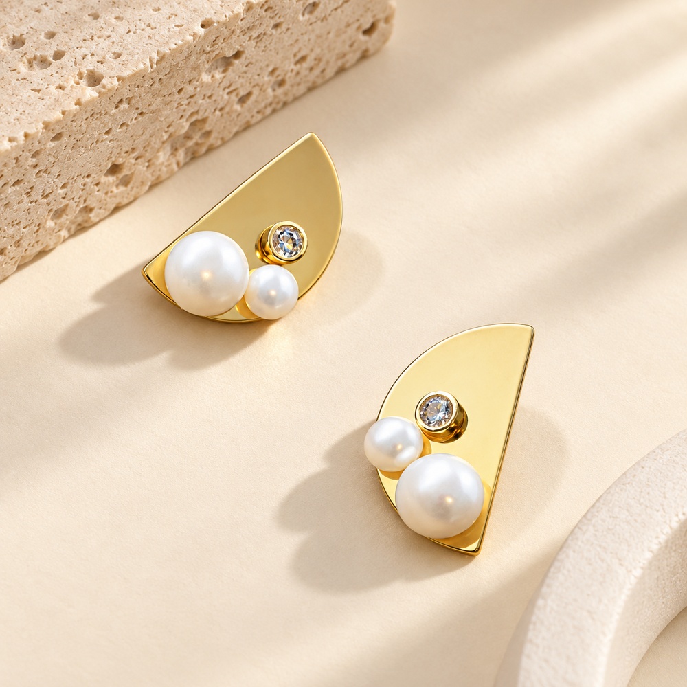 Half-moon gold-tone stud earrings with two pearls and a crystal seen from an angle