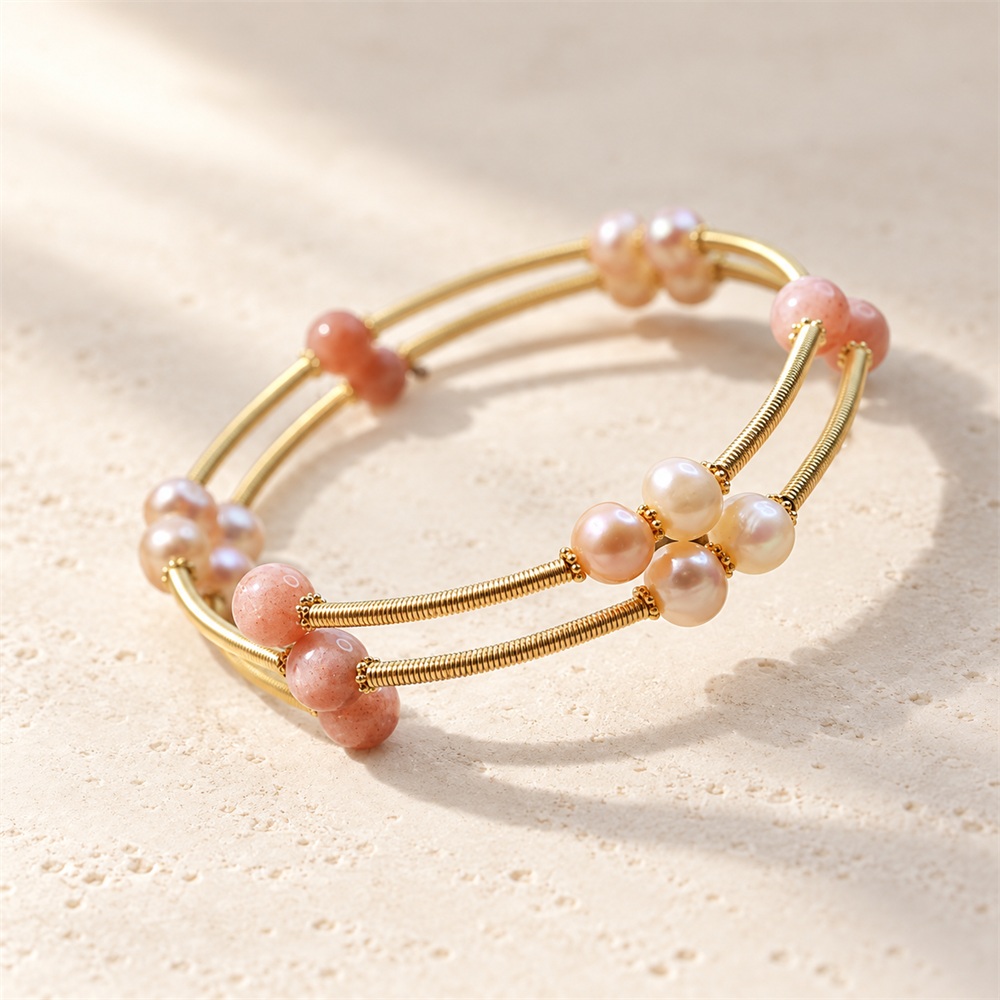 Close view of pink-orange moonstone beads and freshwater pearls on a double-band bangle