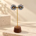 Pair of blue wire crochet pearl daisy studs on a display stand