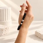 Black obsidian and pearl stretch bracelet shown against a hand