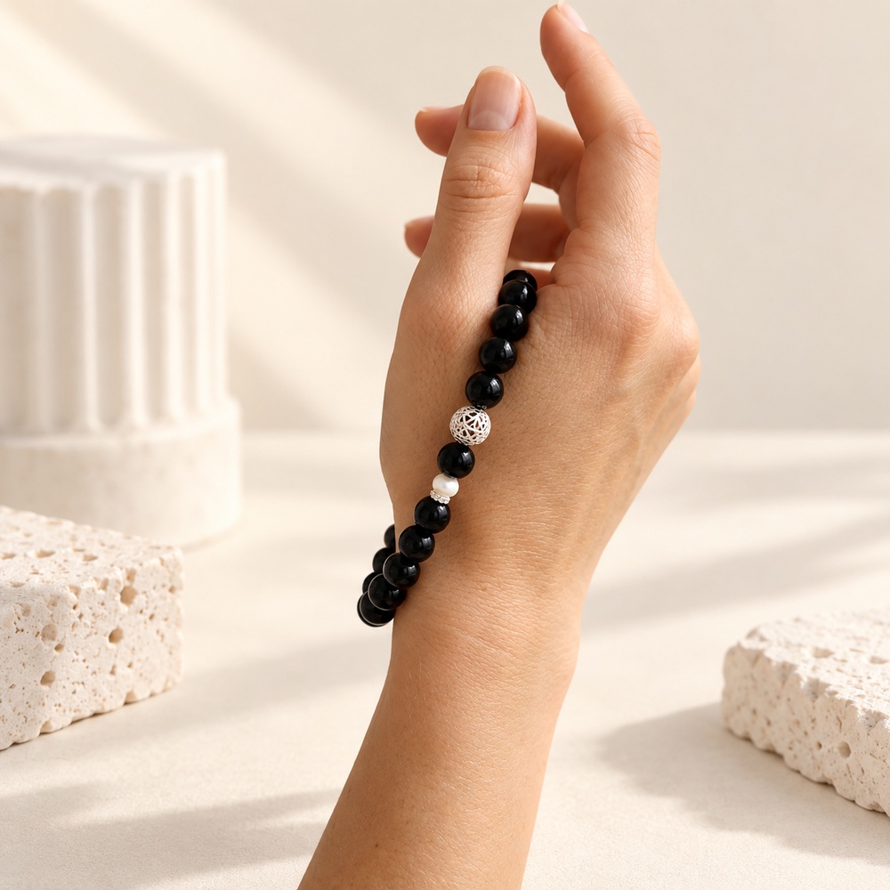 Black obsidian and pearl stretch bracelet shown against a hand