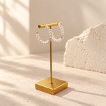 Freshwater pearl open hoop earrings hanging on a T-shaped jewellery display