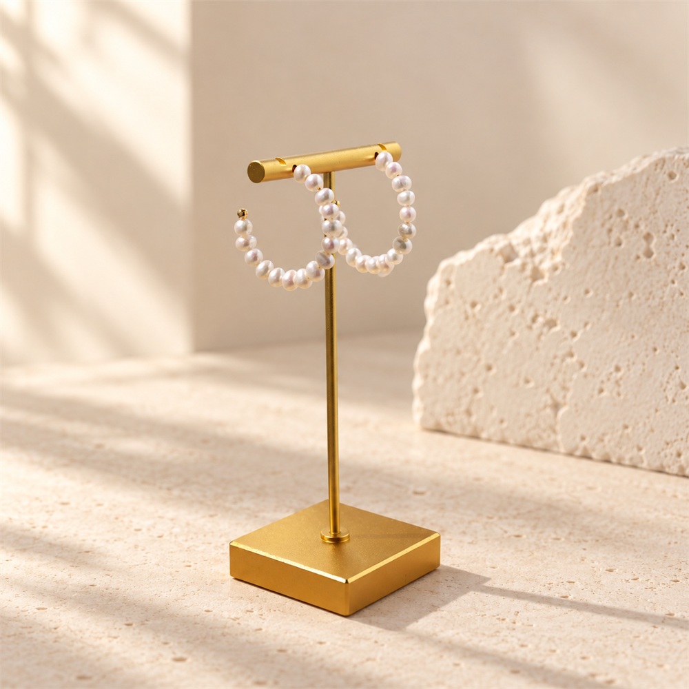 Freshwater pearl open hoop earrings hanging on a T-shaped jewellery display