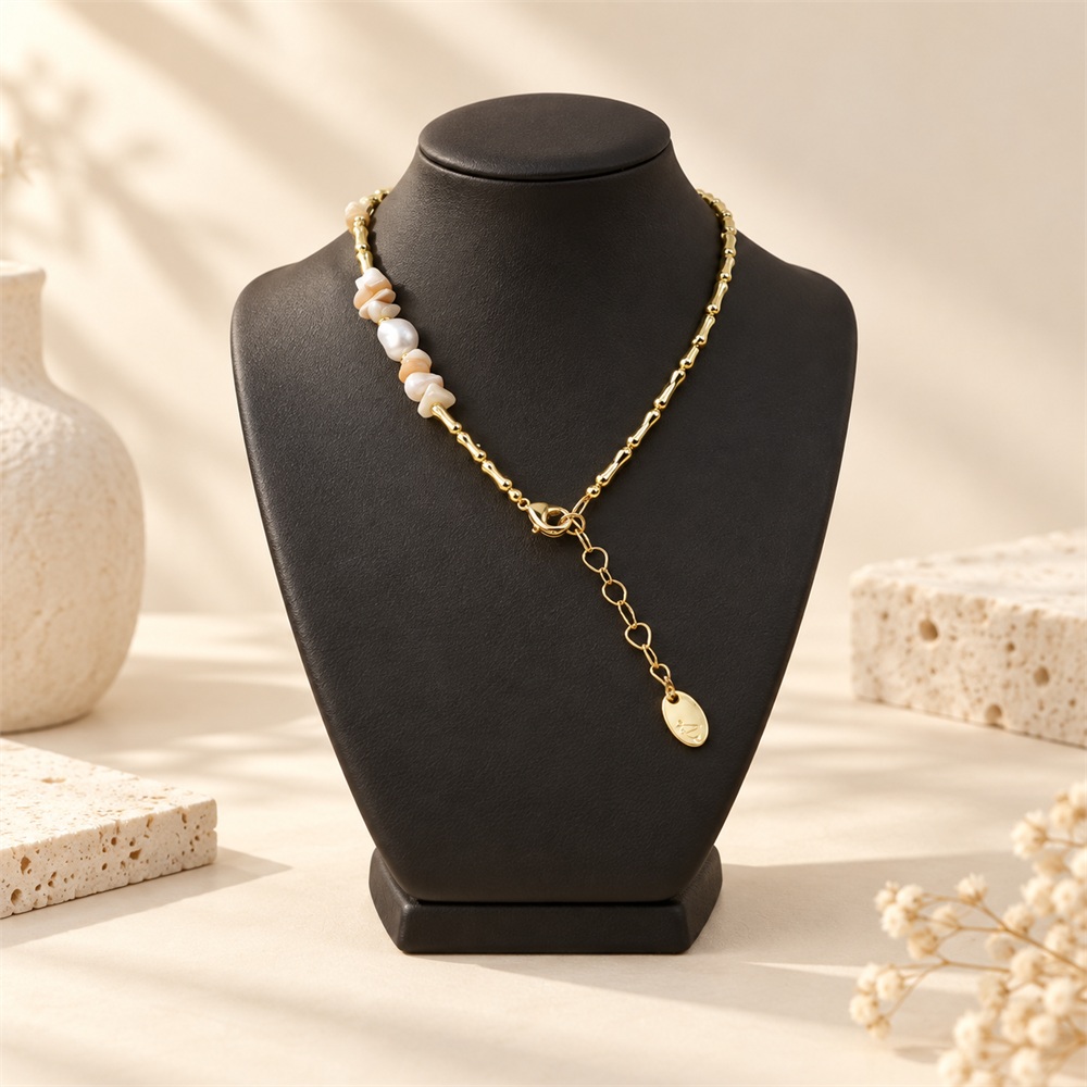 Back view of a shell and pearl necklace on a bust, showing its clasp and extension chain