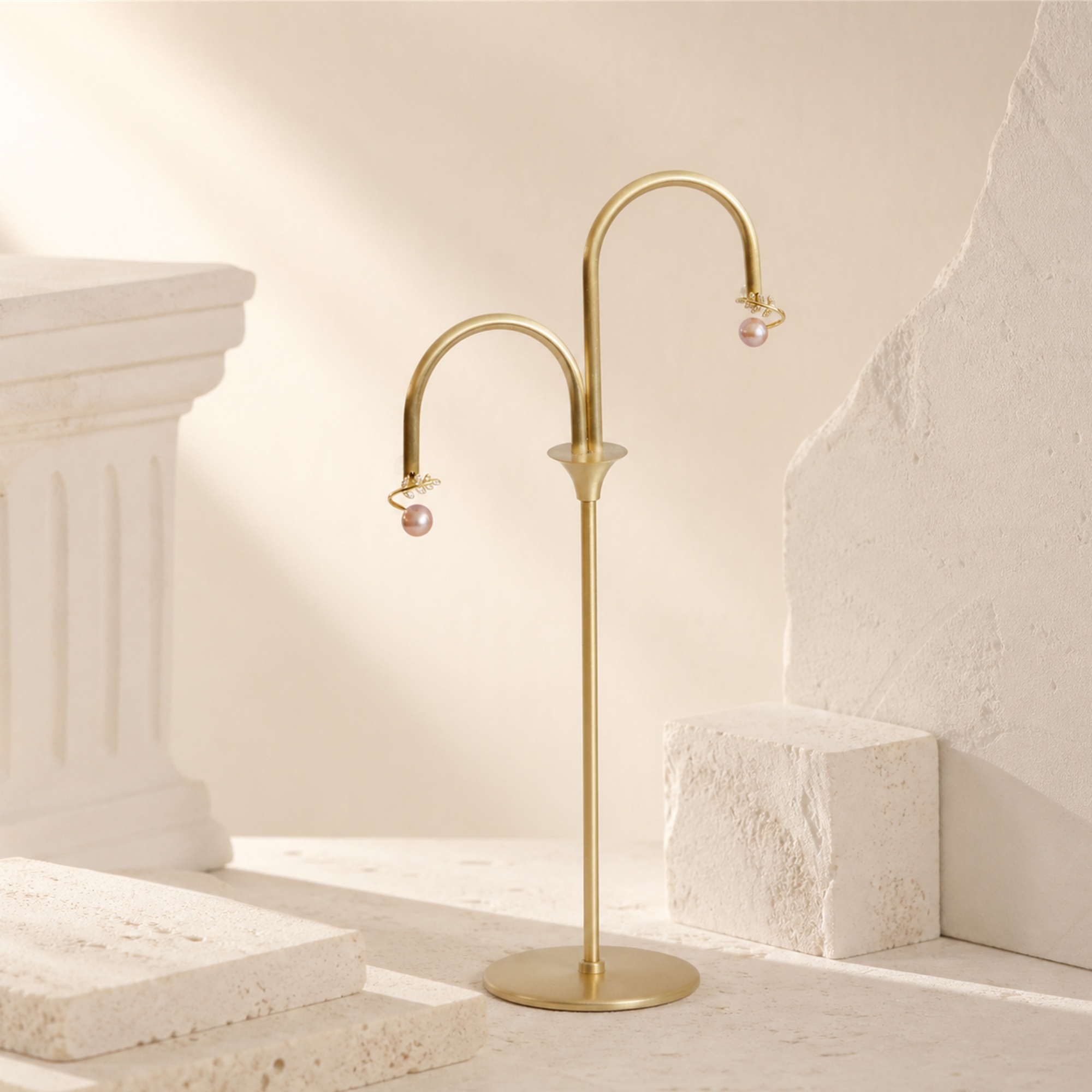 Olive leaf pearl stud earrings on a tall gold-toned display stand