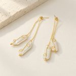 Twin-drop pearl earrings laid flat, showing slender baroque pearls, gold-toned wire curls and stud posts