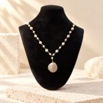 Spiral-wrapped coin pearl necklace displayed on a black bust