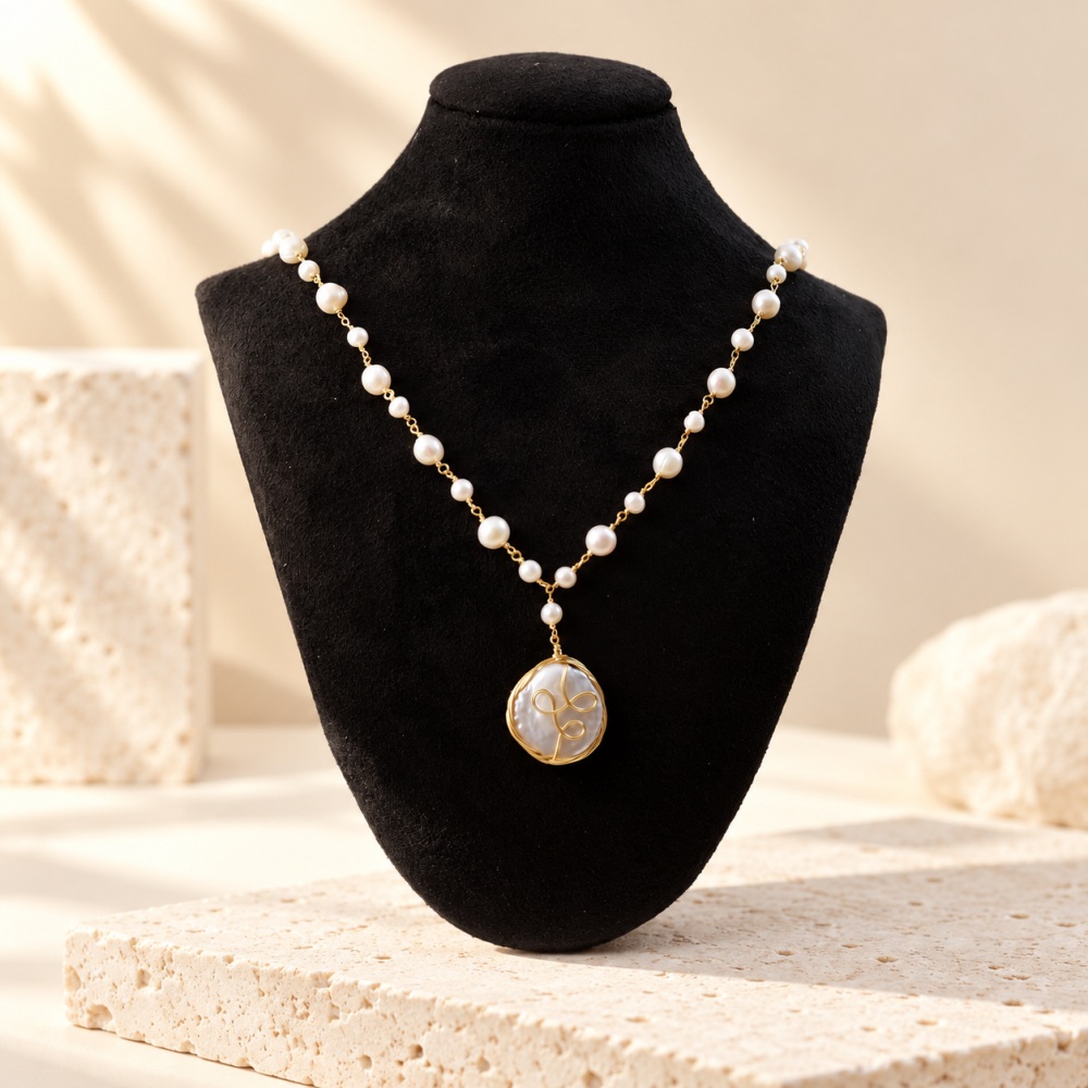 Spiral-wrapped coin pearl necklace displayed on a black bust