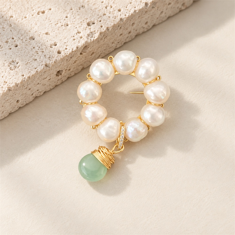 Angled view of pearl circle brooch with dangling green jade bead