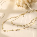 Freshwater pearl long necklace with delicate clear charms laid flat on a white tray