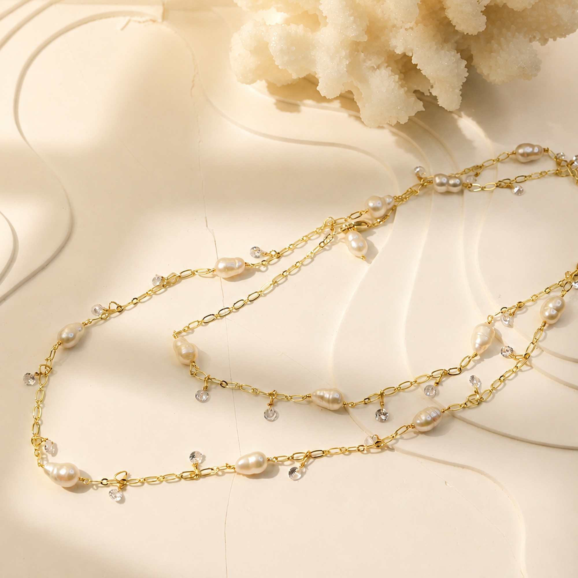 Freshwater pearl long necklace with delicate clear charms laid flat on a white tray
