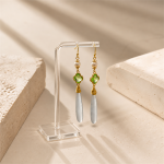 Long green clover and white jade drop earrings hanging on a clear stand