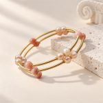 Open gold-tone multi-band bangle with orange moonstone and pearl clusters